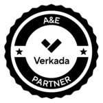 Black and white circular badge with scalloped edges. The center features a checkmark icon above the word Verkada. The top reads A&E and the bottom reads PARTNER, with stars on each side.
