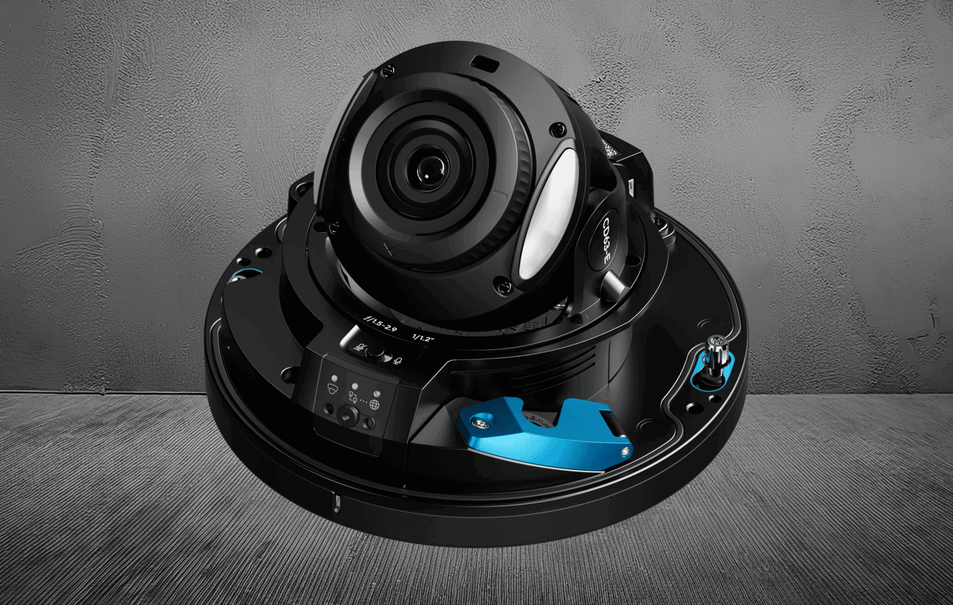 A close-up view of a modern black and blue surveillance camera with multiple lenses, mounted on a circular base, set against a gray textured background.