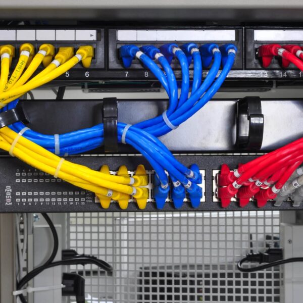 Close-up of a server rack featuring organized yellow, blue, and red cables plugged into labeled patch panels and switches.