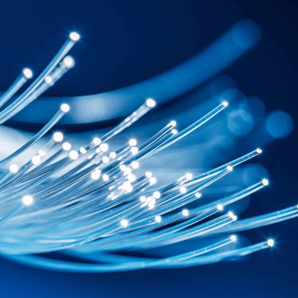 Close-up of glowing fiber optic cables against a blue background, light radiating from tips, symbolizing high-speed data transfer.