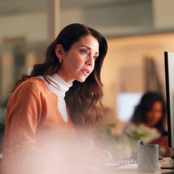 Woman in an office looking at her desktop with concern on her face, as if she has been a victim of a BEC attack